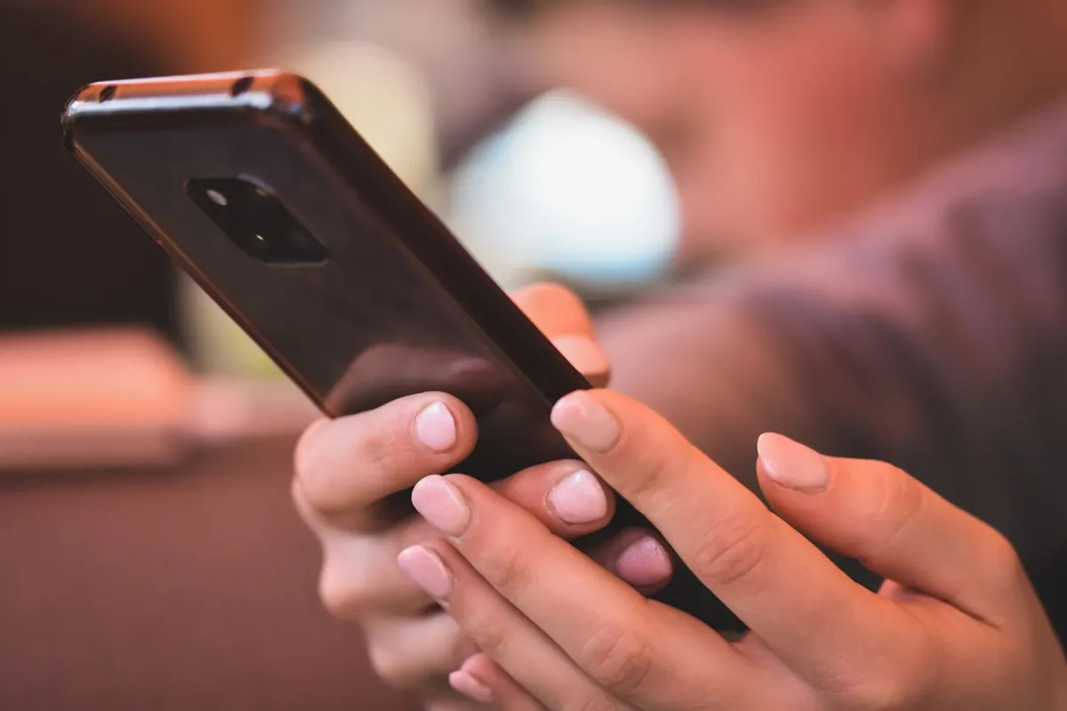 Close-up of two hands holding and operating a phone